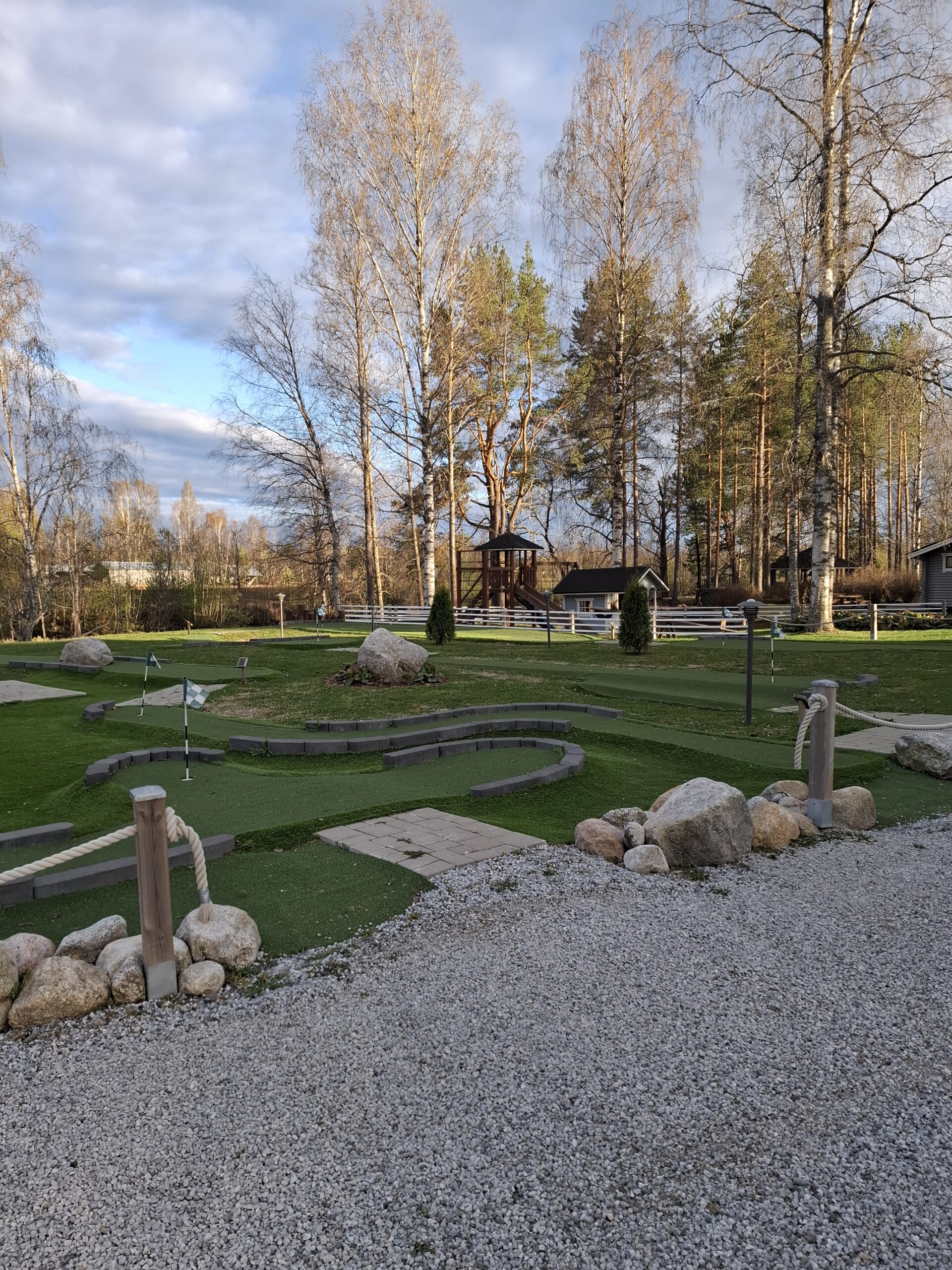 Kuvassa Huhtaniemen Mäkkikylän Adventure Golf -rataa ja pihan keiväistä maisemaa.